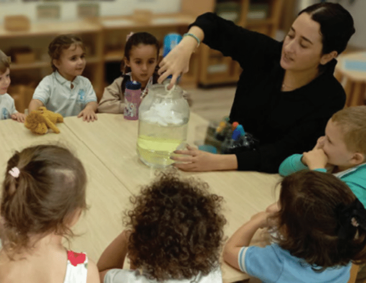 Teacher leading a science activity with young children at a table