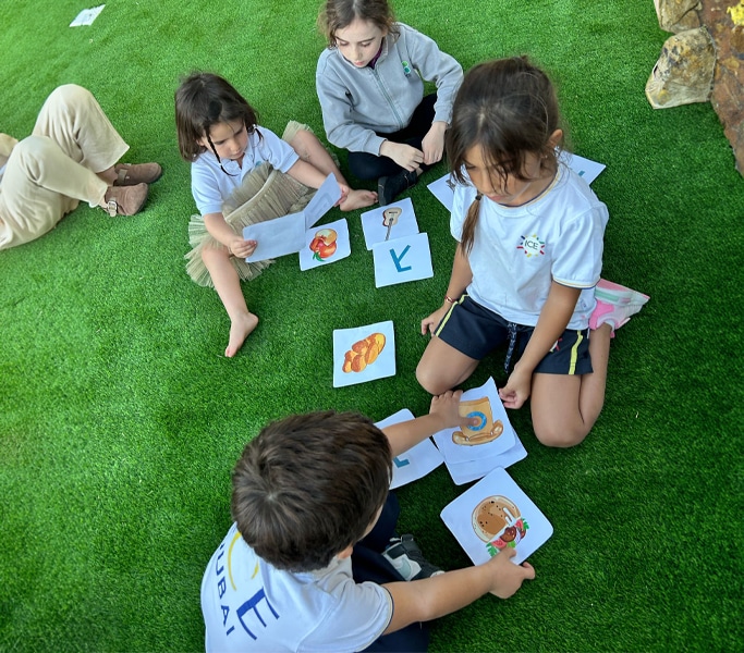 Older student helping a younger child read from a workbook