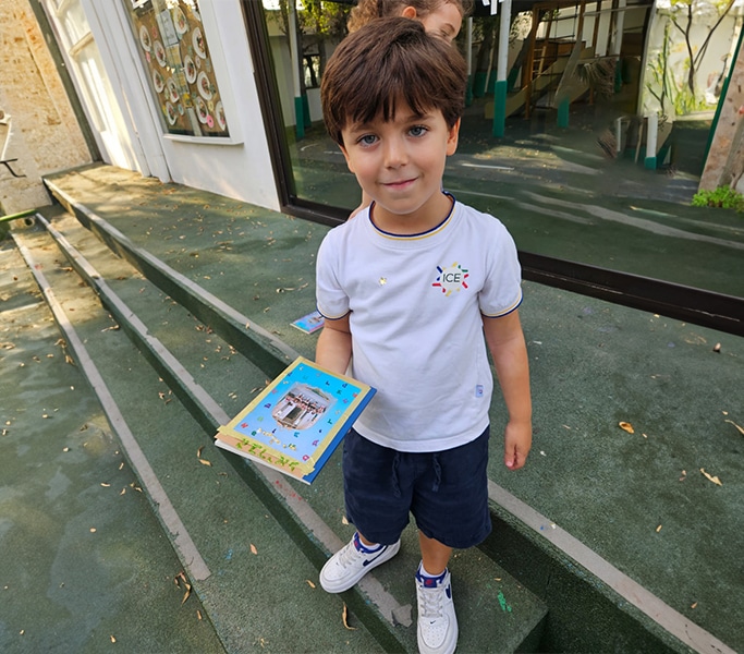 Smiling boy holding a craft project while standing outside