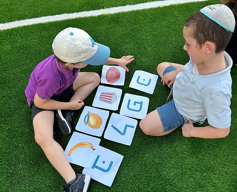 Children matching Hebrew letters on foam tiles outside
