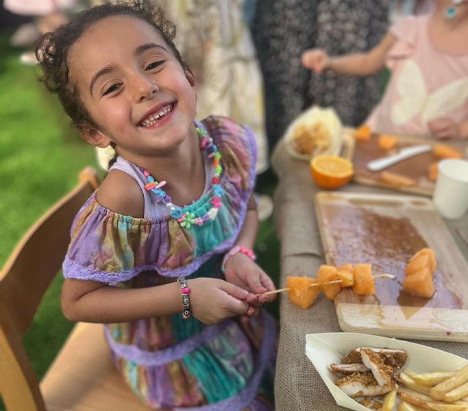 Smiling girl preparing skewers with fried food at an event