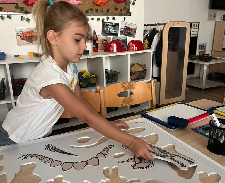 Girl concentrating on assembling puzzle pieces at a table
