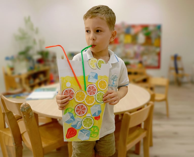 Child holding a decorated paper bag with colorful pipe cleaners