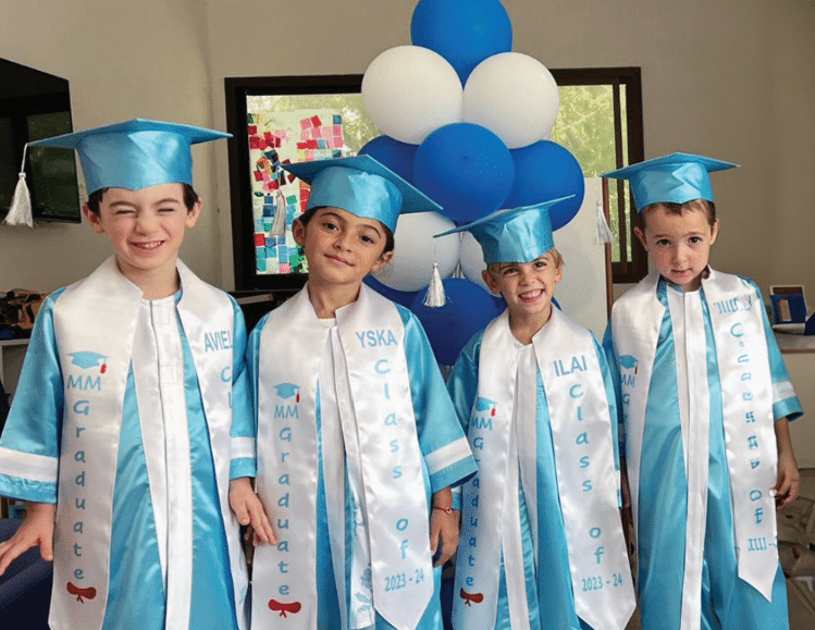 Group of children in blue caps and gowns at graduation ceremony