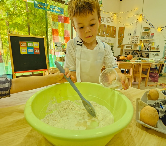 Young child stirring green sensory mixture during activity