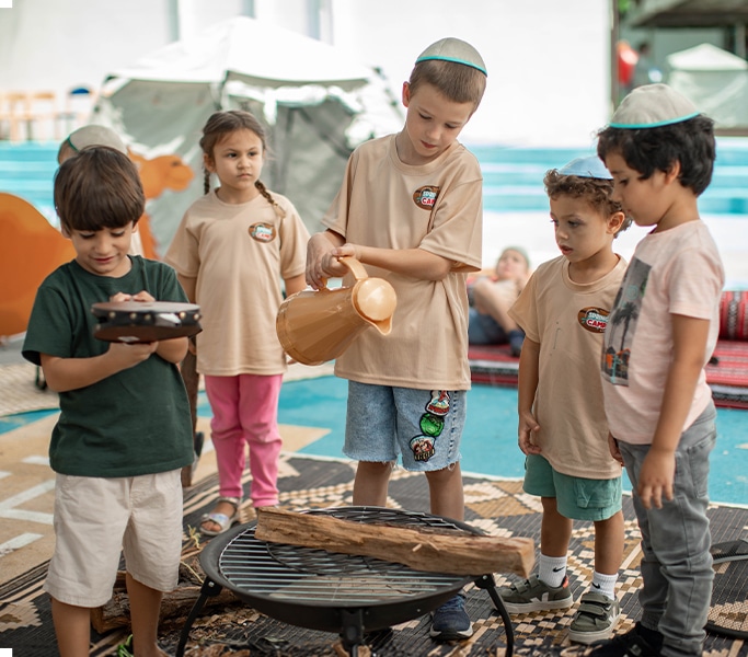 Children gathered around a fire pit roasting marshmallows